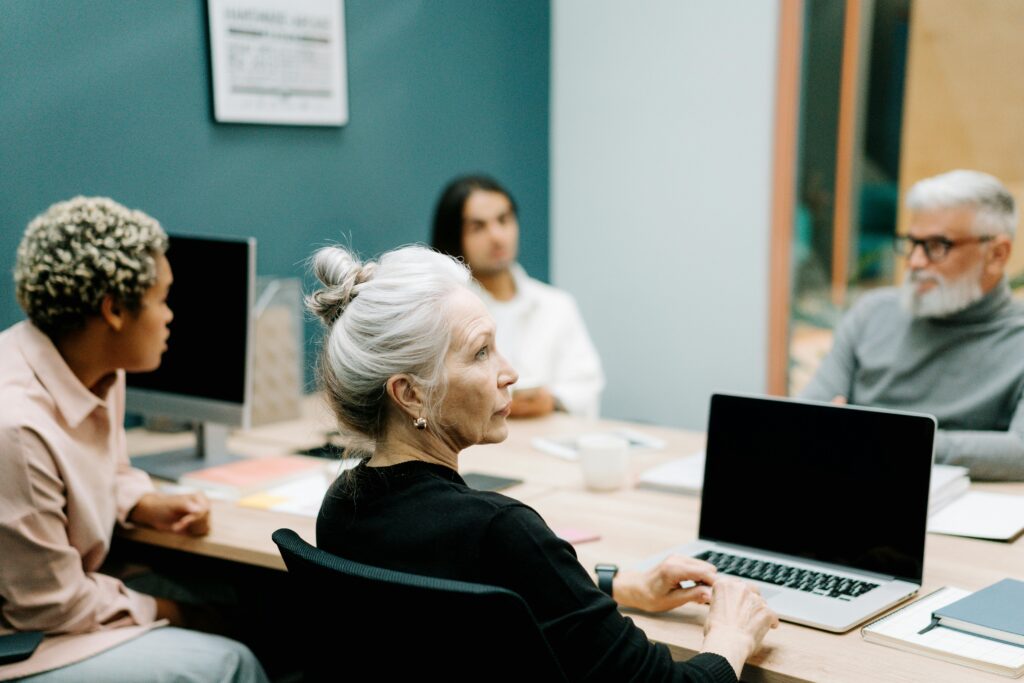 Woman in Black Sweater Sitting on Chair in Front of Macbook Pro